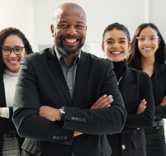 Happy people with arms crossed face the camera in a workplace setting.