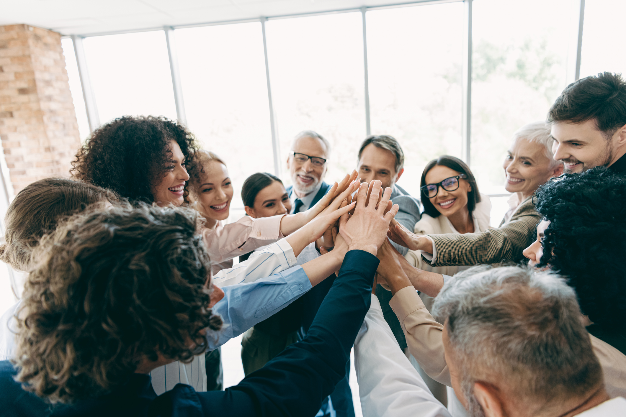 Diverse Group of Professionals Celebrating Partnership and Teamwork in a Modern Office Setting 