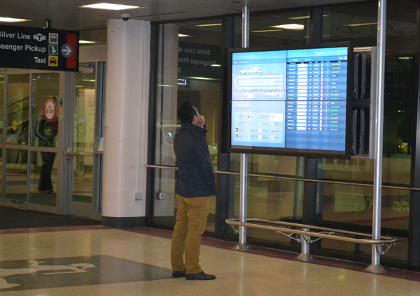A PASSENGER AT BOSTON’S LOGAN INTERNATIONAL AIRPORT VIEWS OPTIONS FOR GROUND TRANSPORTATION FROM THE AIRPORT. ARORA ENGINEERS DESIGNED MOST OF THE DIGITAL SIGNS IN USE AT LOGAN.