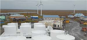 THE	KASIGLUK	MICRO-GRID--BULK	FUEL	TANK	FARM	SHOWN	IN	THE	FOREGROUND	WITH	POWERPLANT	AND	WIND	TURBINES	THAT	ALSO	CONTRIBUTE	POWER	TO	KASIGLUK’S	MICROGRID	BEHIND.